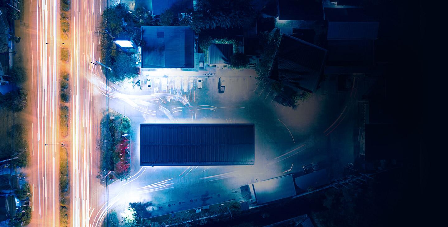 Arial view of a business at night with car lights streaming by on the street